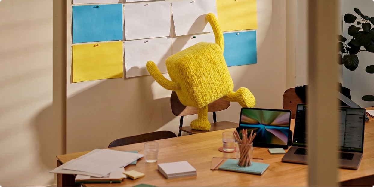 Garba mid-leap over a desk in front of a wall of sticky notes