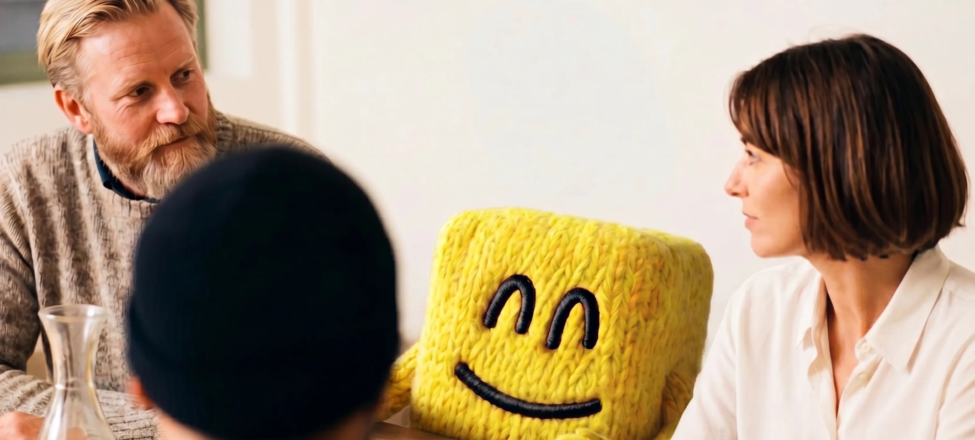 Two people meeting with Garba, the knitted yellow mascot, on the table